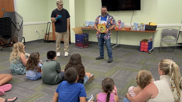 Two instructors teaching children from How to Make Your Sock Talk during a library ventriloquism workshop