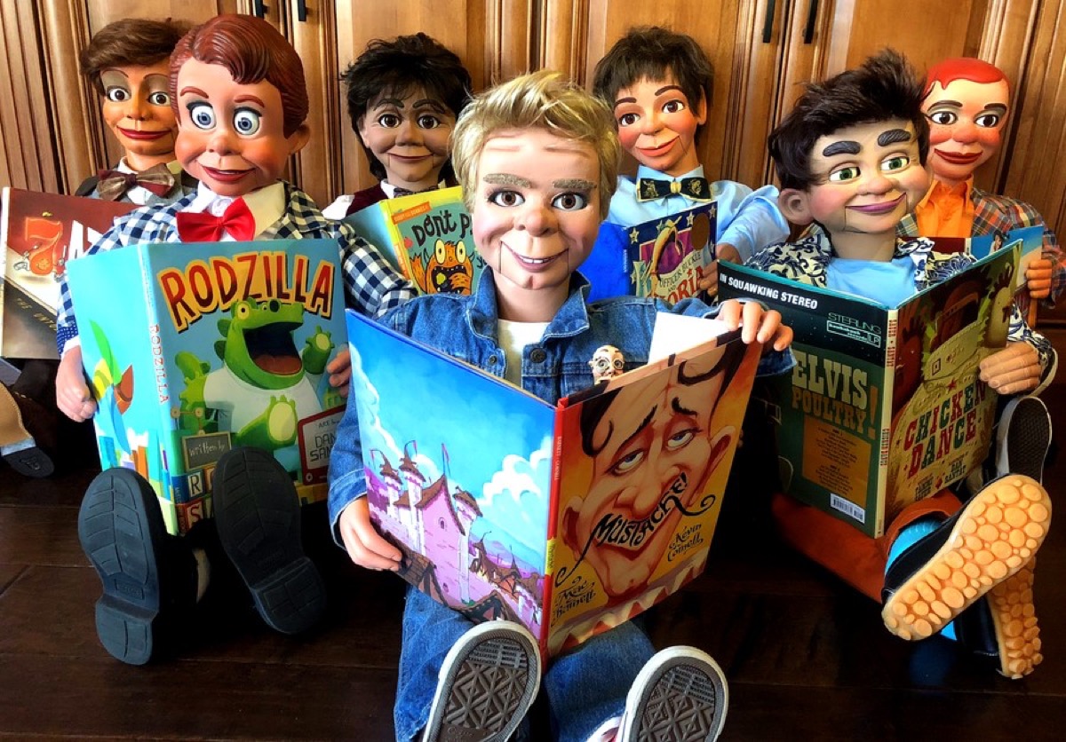 Eight ventriloquial figures seated with open picture books